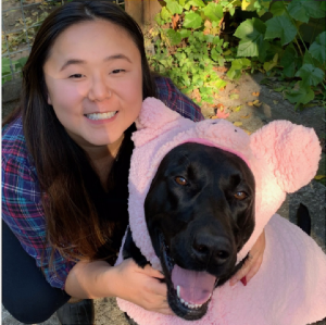 Lucia with a large black dog in a pink sweater Lucia with a large black dog in a pink sweater